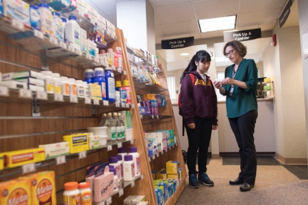 A student talking with a professor inside Pharmacy store