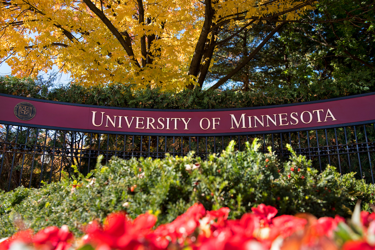 UMN sign on iron gate in colorful summer garden