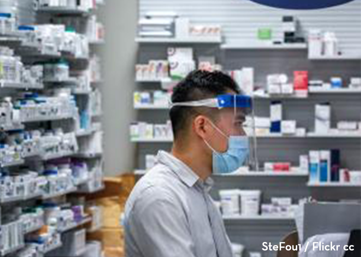 pharmacist standing in pharmacy with face mask and face shield