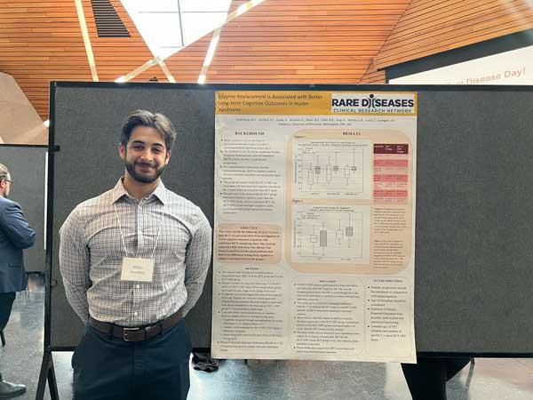 Man smiling and standing in front of his research poster 